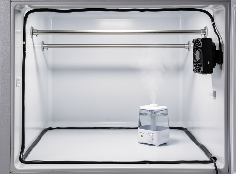 Interior view of fridge curing chamber showing modifications — small ultrasonic humidifier on bottom shelf, USB fan attached to side wall, stainless steel rods in upper section, black silicone sealant around door gaskets