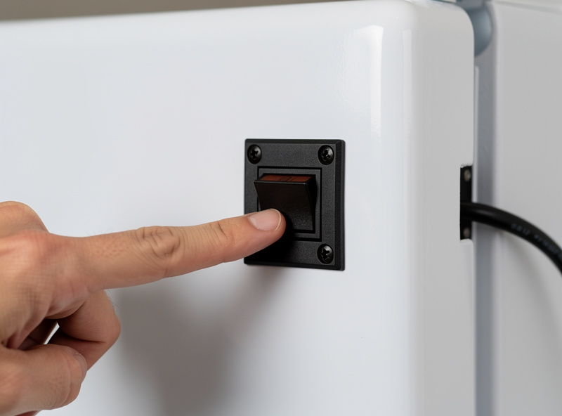 Momentary rocker switch mounted on the outside of a white mini fridge door for external light control