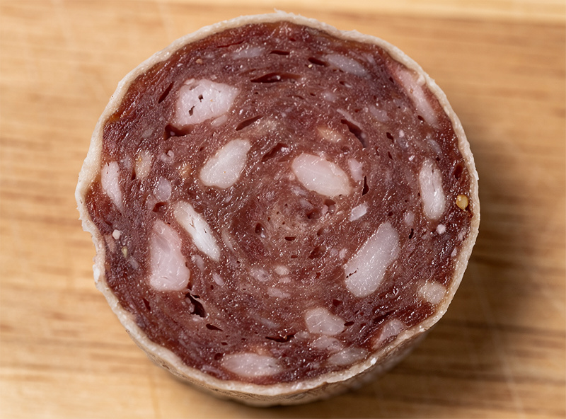 Cross-section of a case-hardened salami showing hard outer rind with wet center inside