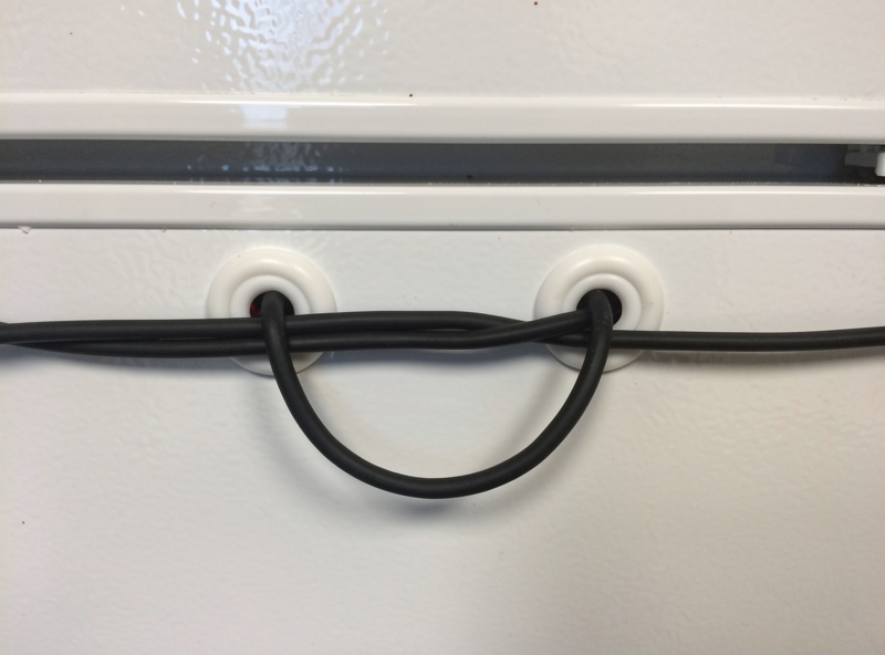 Rubber grommets sealing probe wires through a drilled fridge door with service loop and silicone seal
