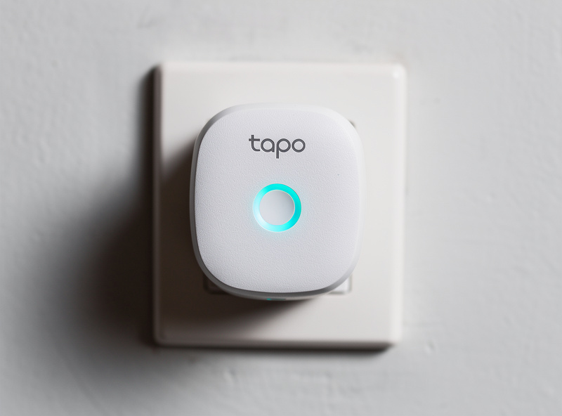 Close-up of a smart plug installed in a wall outlet with status LED illuminated