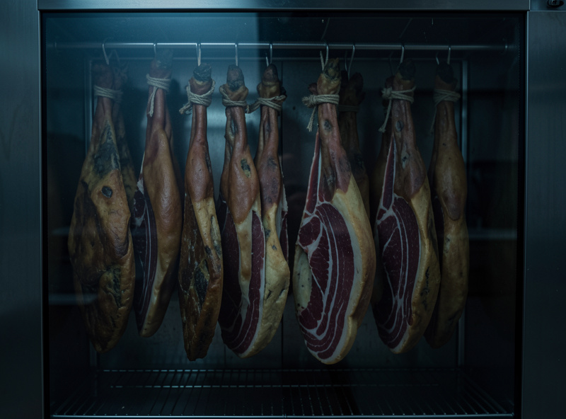 Dry-cured coppa and pancetta hanging in a home curing chamber